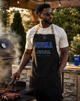 Sigma fraternity brother wearing a black grilling apron while cooking outdoors at a barbecue with a smoker