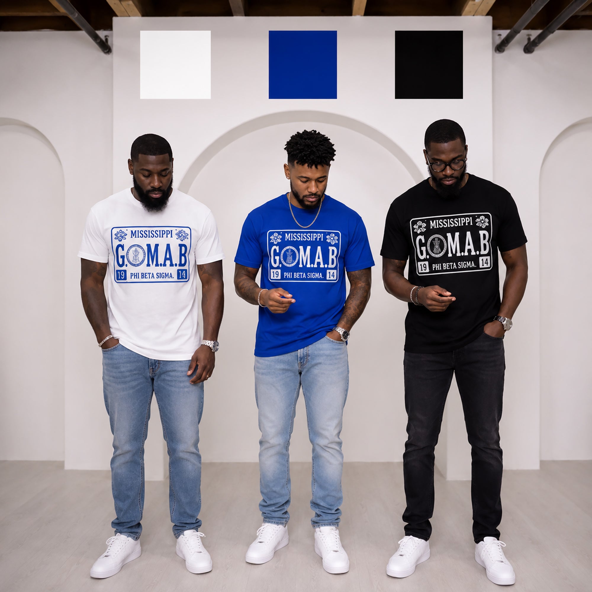 Three men wearing white, blue, and black G.O.M.A.B. Phi Beta Sigma T-shirts