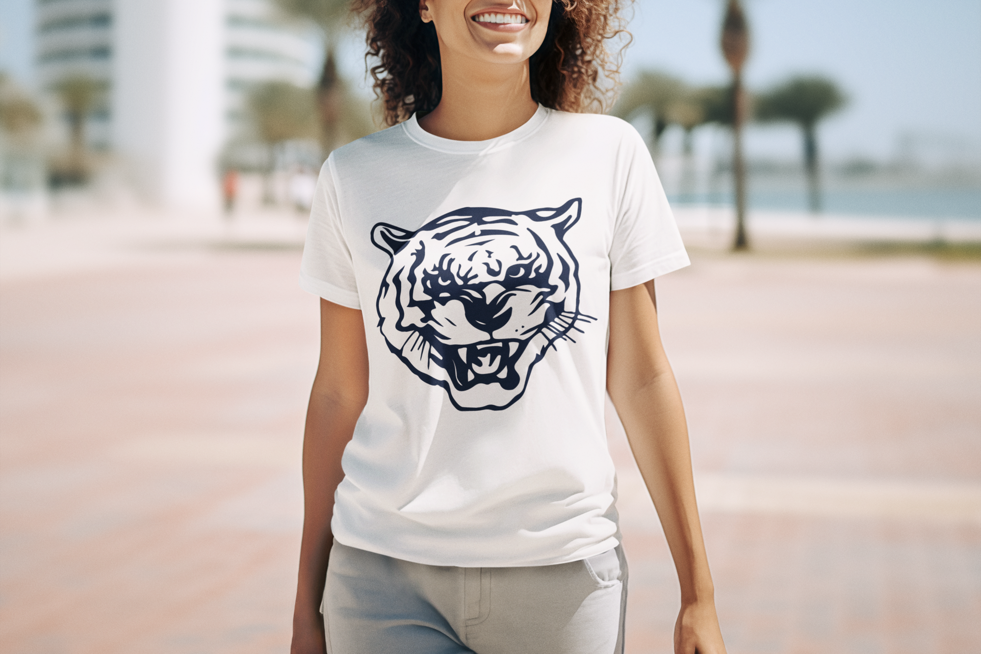 White crewneck T-shirt with blue tiger head logo, worn by a smiling woman
