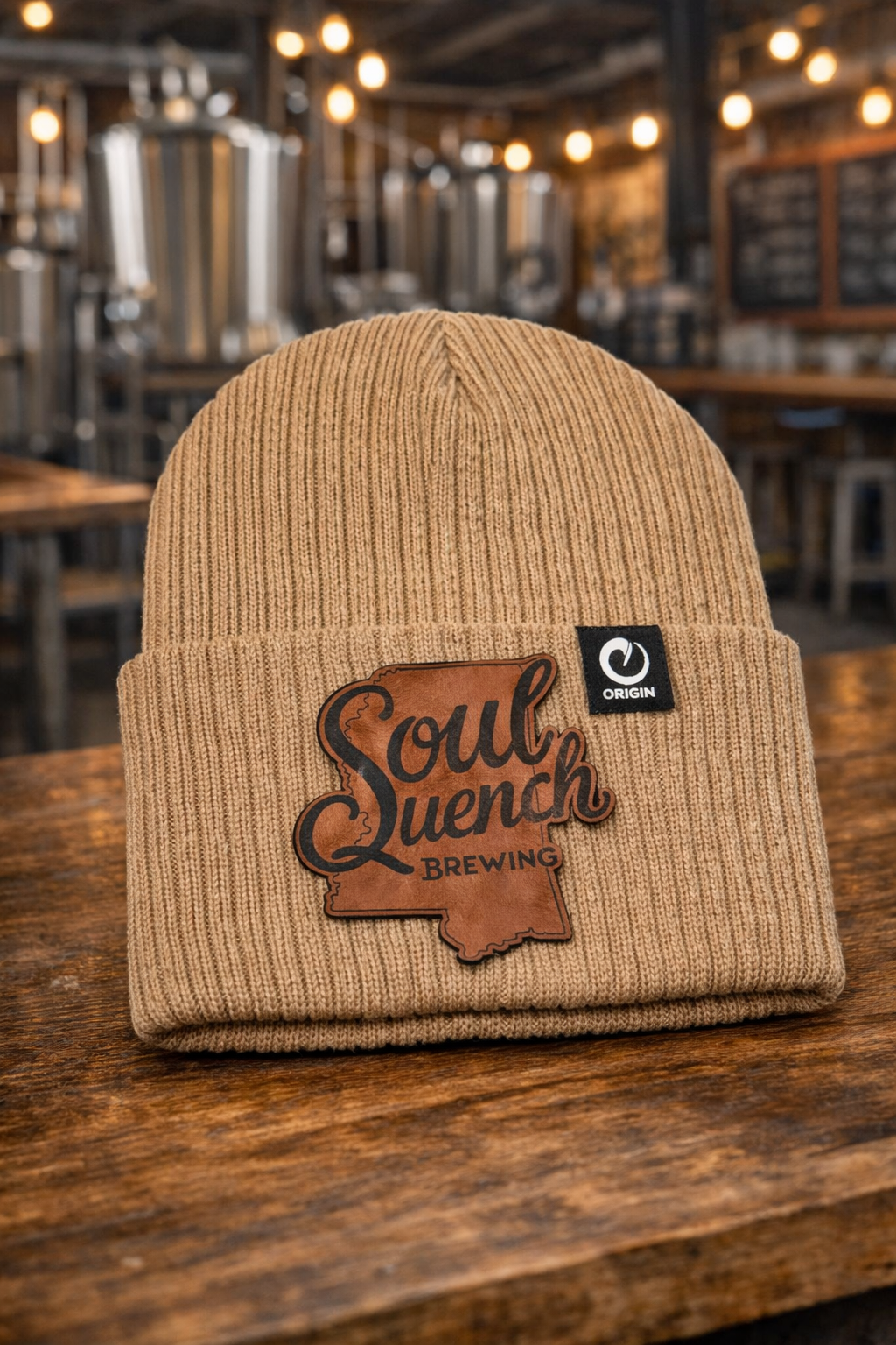Custom Soul Quench Brewing beanies featuring Mississippi state logo patch in walnut to black photographed in a brewery.