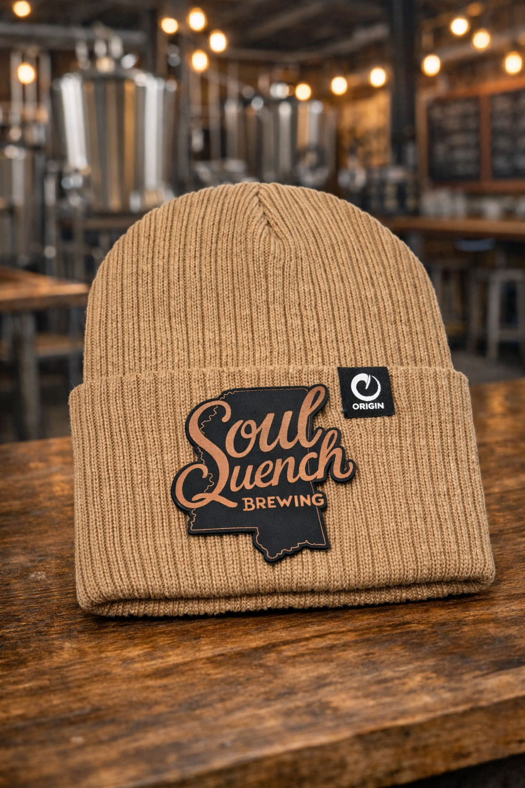 Custom Soul Quench Brewing beanies featuring Mississippi state logo patch in black to copper photographed in a brewery.