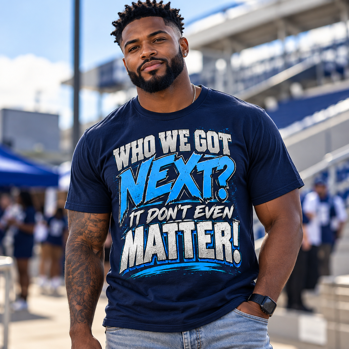 Black man wearing navy Who We Got Next It Don't Even Matter T-shirt at a game-day stadium setting