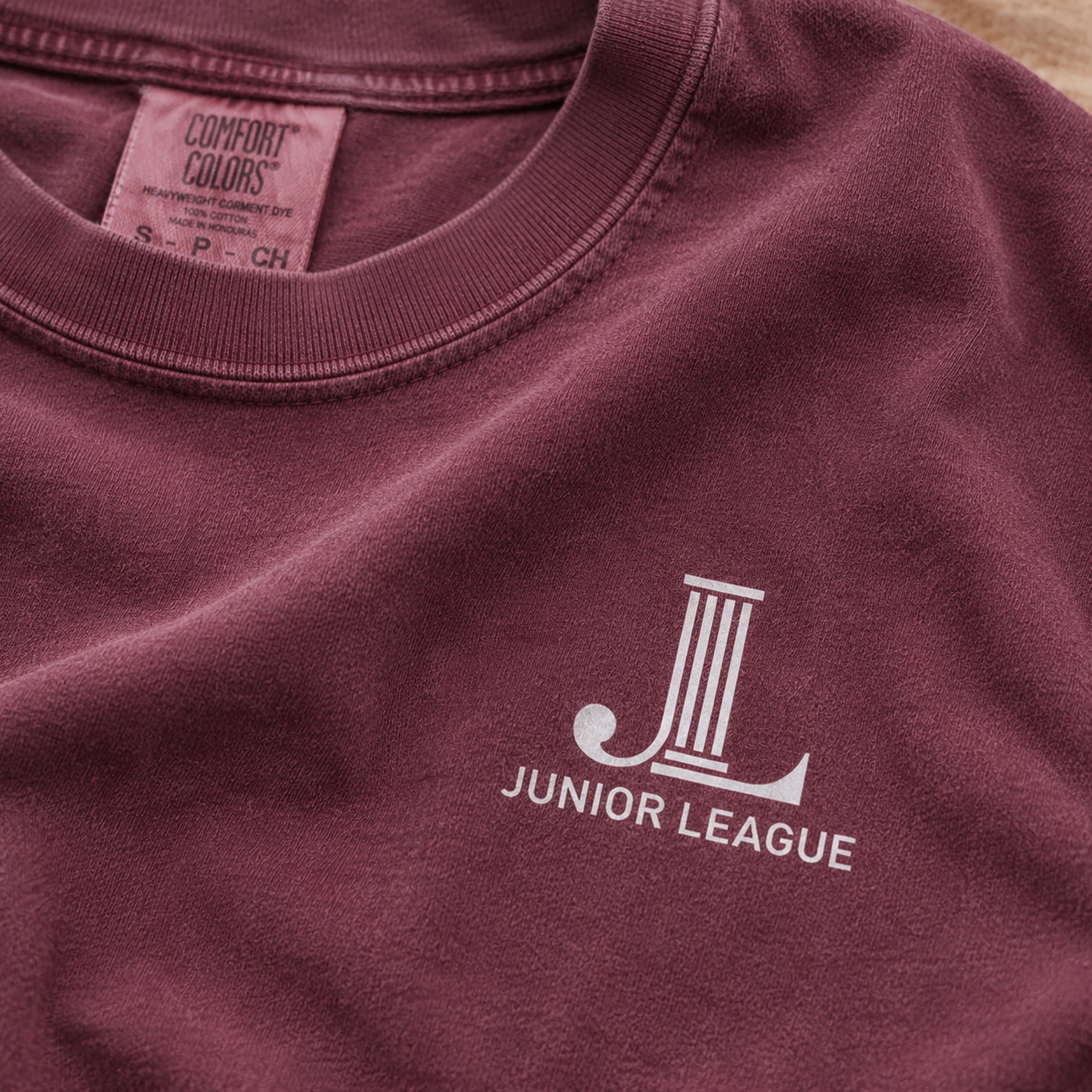 Close-up of the front chest JL logo on the Women Who Build Beach Wash Tee