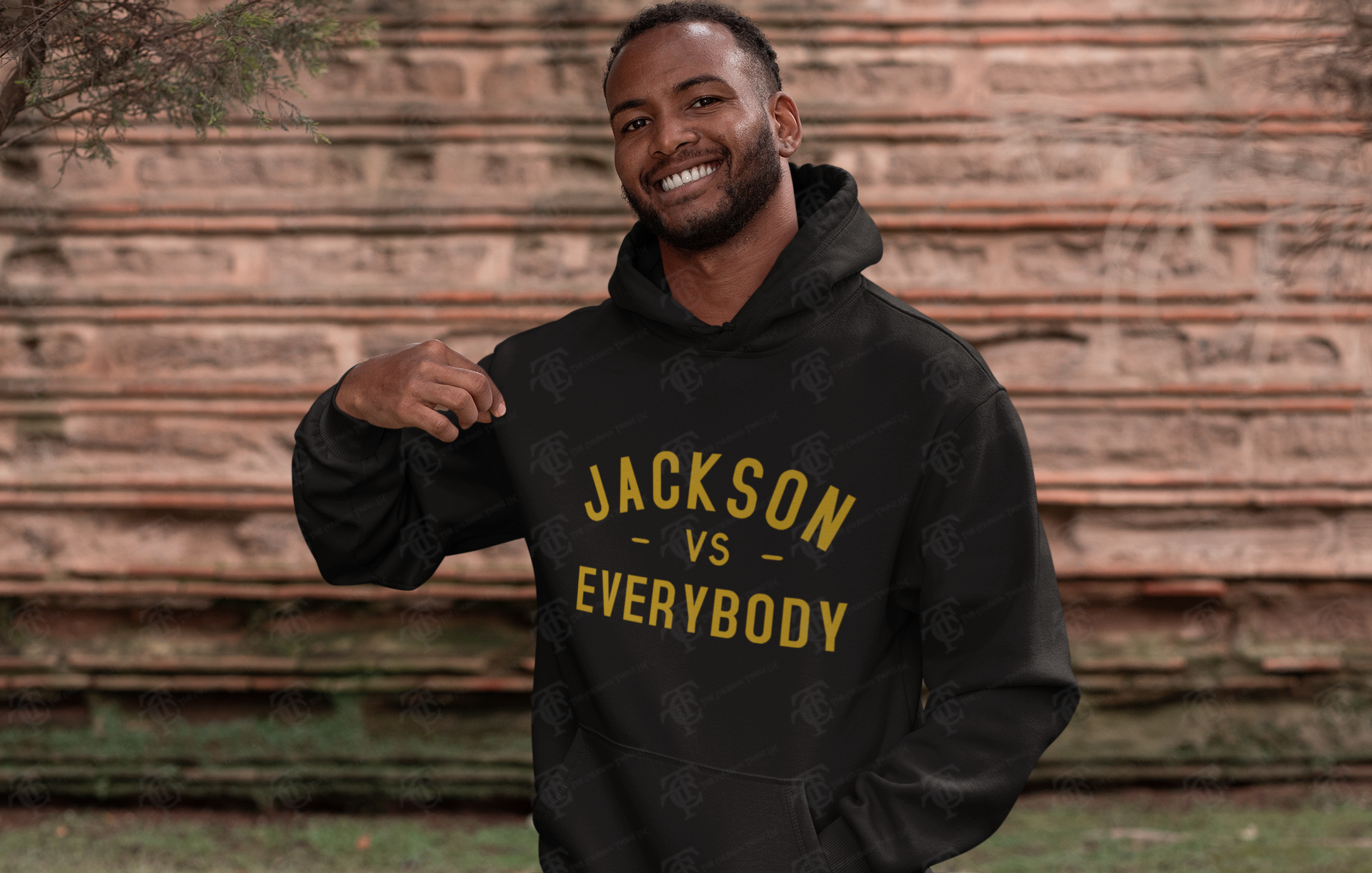 Black pullover hoodie worn, with gold 'JACKSON VS EVERYBODY' front print and drawstring hood