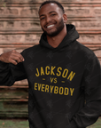 Black pullover hoodie worn, with gold 'JACKSON VS EVERYBODY' front print and drawstring hood