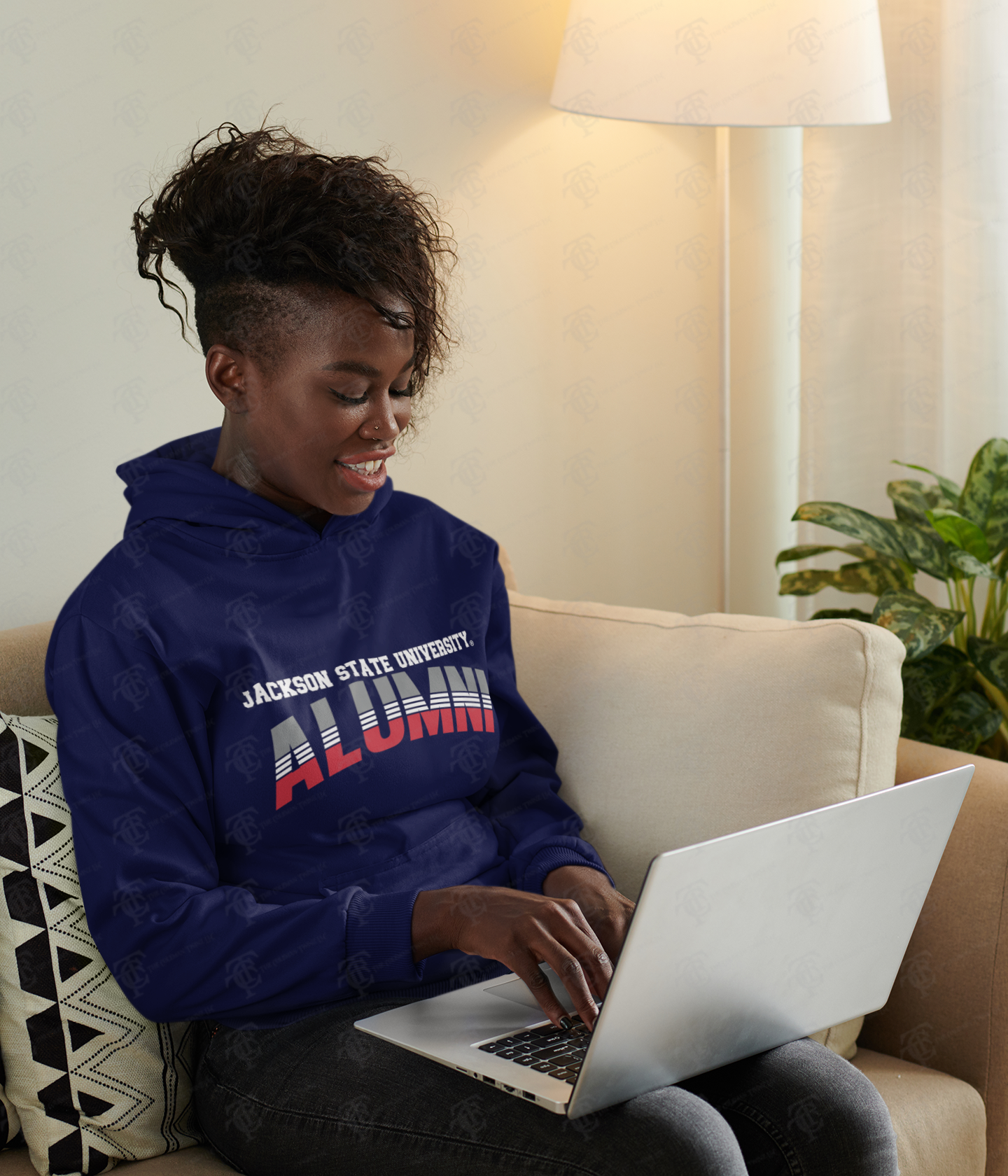 Navy unisex pullover hoodie with “Alumni” chest logo, worn by a seated person